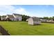 Spacious backyard with lush green grass, privacy fence, a large deck, and a storage shed at 30 Sunbury Ct, Zebulon, NC 27597
