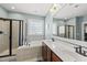 Well-lit bathroom with a tiled bathtub, a glass shower, and a double vanity at 300 Redhill Rd, Holly Springs, NC 27540
