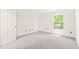 Sunlit bedroom with neutral carpet, white trim, and views of the surrounding trees at 304 W Kirkfield Dr, Cary, NC 27518