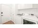 Bright laundry room with front load washer and dryer with upper white storage cabinets at 304 W Kirkfield Dr, Cary, NC 27518