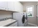 Bright laundry room with upper cabinets, a sink, modern washer, dryer, and a window at 3128 Mountain Hill Dr, Wake Forest, NC 27587