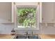 Sunlit kitchen sink beneath a window, featuring tile backsplash and plenty of natural light at 3329 Broughton Dr, Durham, NC 27704