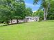 Charming single-story home with a combination brick and white exterior, surrounded by lush trees and a green lawn at 4605 Malor Dr, Wake Forest, NC 27587