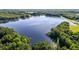 An aerial view of a large lake surrounded by lush trees under a clear blue sky at 4701 Governor Hunt St, Efland, NC 27243