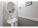 Charming powder room with pedestal sink, round mirror, and stylish wainscoting at 509 Spruce Meadows Ln, Willow Springs, NC 27592
