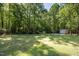 Large, grassy backyard with mature trees and a shed in the distance at 560 Parker Creek Rd, Holly Springs, NC 27540