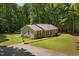 Inviting single-story home with a metal roof, gravel driveway, and surrounded by lush greenery at 560 Parker Creek Rd, Holly Springs, NC 27540