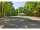 View of a cute house nestled in the trees, featuring a wide circle driveway and a metal roof at 560 Parker Creek Rd, Holly Springs, NC 27540