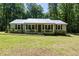 Charming single-story home with a metal roof and covered front porch, surrounded by lush greenery at 560 Parker Creek Rd, Holly Springs, NC 27540