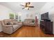 Bright living room featuring hardwood floors, comfortable seating, and a ceiling fan for added comfort at 560 Parker Creek Rd, Holly Springs, NC 27540