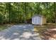 Backyard shed with gravel driveway surrounded by mature trees at 560 Parker Creek Rd, Holly Springs, NC 27540