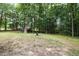 Lush backyard with mature trees and a fire pit, perfect for outdoor enjoyment at 687 W Watson Rd, Benson, NC 27504