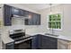 Modern kitchen with navy blue cabinets, stainless steel appliances, and bright window at 856 Williams White Rd, Zebulon, NC 27597