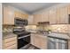 Well-lit kitchen featuring stainless steel appliances, wooden cabinetry, and tiled backsplash at 8610 Neuse Landing Ln # 103, Raleigh, NC 27616