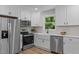 Well-lit kitchen boasts stainless steel appliances, white cabinets, and a stylish subway tile backsplash at 908 W Garden St, Sanford, NC 27330