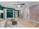 A well-lit living room featuring dark green walls, brick wall, and modern ceiling fan at 908 W Garden St, Sanford, NC 27330
