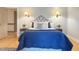 A bedroom with hardwood floors, two end tables with wall lamps and a blue comforter on the bed at 9417 Greenfield Dr, Raleigh, NC 27615