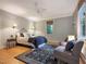 Light and airy bedroom features a bed with two end tables, ceiling fan, sitting area and two windows at 9417 Greenfield Dr, Raleigh, NC 27615