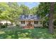 Charming home with a covered front porch, well-manicured lawn, and mature trees, offering a tranquil setting at 9417 Greenfield Dr, Raleigh, NC 27615