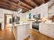 A well-lit kitchen with an island, stainless steel appliances, white cabinets and beautiful wood ceiling beams at 9417 Greenfield Dr, Raleigh, NC 27615
