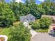 Expansive aerial view of a white home with lush trees, private backyard, and curved driveway at 1001 Dairy House Ct, Wake Forest, NC 27587