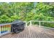 Open deck with a grill and railing, perfect for outdoor cooking and entertaining surrounded by lush green trees at 1001 Dairy House Ct, Wake Forest, NC 27587