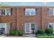 Brick townhome featuring symmetrical design, vibrant purple shutters, and well-manicured greenery at 103 Coleridge Ct, Carrboro, NC 27510