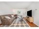 Open living room with a large comfortable couch, big screen television, and hardwood floors at 103 Coleridge Ct, Carrboro, NC 27510