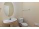 Half bathroom with a pedestal sink, toilet, and a decorative mirror at 1031 Lake Moraine Pl, Raleigh, NC 27607