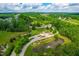 Aerial view showing lush green landscape, a pond with fountain, winding roads, and beautiful homes at 113 Hidden Bluff Dr, Chapel Hill, NC 27517