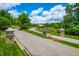 Upscale community entrance featuring stone pillars, lush landscaping, and a curved roadway for a welcoming approach at 113 Hidden Bluff Dr, Chapel Hill, NC 27517