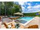 Stunning backyard pool with a built-in spa, in-water loungers, and a lush forest backdrop at 113 Hidden Bluff Dr, Chapel Hill, NC 27517