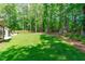 A serene backyard boasts lush lawn, mature trees, a shed, and a fenced perimeter at 11817 Coachmans Way, Raleigh, NC 27614