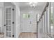 Bright foyer featuring light wood floors, a white front door with glass panes, and modern lighting fixture at 11817 Coachmans Way, Raleigh, NC 27614