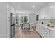 Bright kitchen features all-white cabinets, stainless steel appliances, and a dining area near a large window at 11817 Coachmans Way, Raleigh, NC 27614