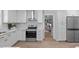 Another angle of all-white kitchen featuring stainless steel appliances, subway tile backsplash, and open layout at 11817 Coachmans Way, Raleigh, NC 27614