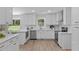 Bright, all-white kitchen with stainless steel appliances, modern countertops, and a view to the landscaped backyard at 11817 Coachmans Way, Raleigh, NC 27614