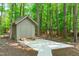 A shed with a concrete pad is located among the mature trees in the back yard at 11817 Coachmans Way, Raleigh, NC 27614