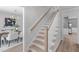 Staircase with light wood treads, white risers and railing, with view into a dining room with chandelier at 11817 Coachmans Way, Raleigh, NC 27614