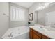 A large soaking tub sits under a window with plantation shutters, next to a vanity with cherry cabinetry at 12505 Garden Tree Ln, Raleigh, NC 27614
