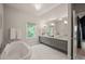 Bright bathroom with double sinks, oversized tub, gray cabinets, and marble flooring at 129 Ruskin Dr, Chapel Hill, NC 27516