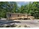 Back exterior featuring tan siding and a wooden ramp for easy access and serene wooded setting at 130 S Creek Dr, Louisburg, NC 27549