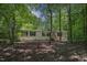 Front exterior featuring neutral siding, black shutters, mature trees, and a serene wooded setting at 130 S Creek Dr, Louisburg, NC 27549