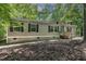 Charming single-story home featuring vinyl siding, black shutters, and a wooden porch nestled in a lush wooded setting at 130 S Creek Dr, Louisburg, NC 27549