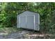 Exterior view of a gray metal shed surrounded by trees and underbrush at 130 S Creek Dr, Louisburg, NC 27549
