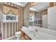 Bathroom with patterned wallpaper, sink vanity, decorative mirror, and window with privacy curtain at 1325 Red Brick Rd, Garner, NC 27529
