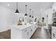 White kitchen boasts a spacious island, dark hardware, wood floors, and seamless flow into dining at 142 Benson Village Dr # 82, Benson, NC 27504