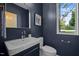 Modern powder room featuring navy walls, floating vanity, and an arched mirror above sink at 160 Daphine Dr, Hillsborough, NC 27278