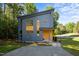 Modern exterior with gray siding, wood accents, and gravel driveway, nestled in a lush, green setting at 160 Daphine Dr, Hillsborough, NC 27278