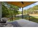 Covered porch with stylish seating, geometric rug, black railings, and wooded view at 160 Daphine Dr, Hillsborough, NC 27278